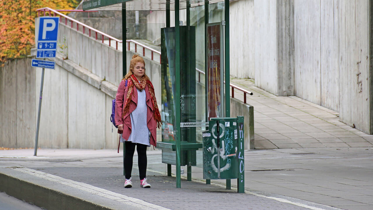 Nainen seisoo bussipysäkillä